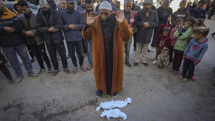 Palestinos rezan frente a los cuerpos de dos bebés fallecidos por hipotermia en Gaza. (Foto: AP)