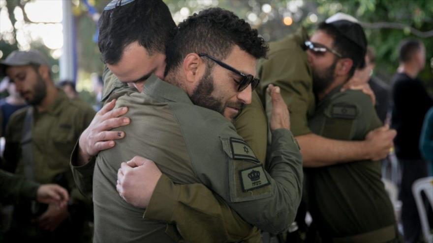 Los soldados israelíes se consuelan entre sí en el funeral del sargento mayor, Akiva Yasinsky, en un cementerio en Tel Aviv, 10 de enero de 2024. (Foto: Flash90)