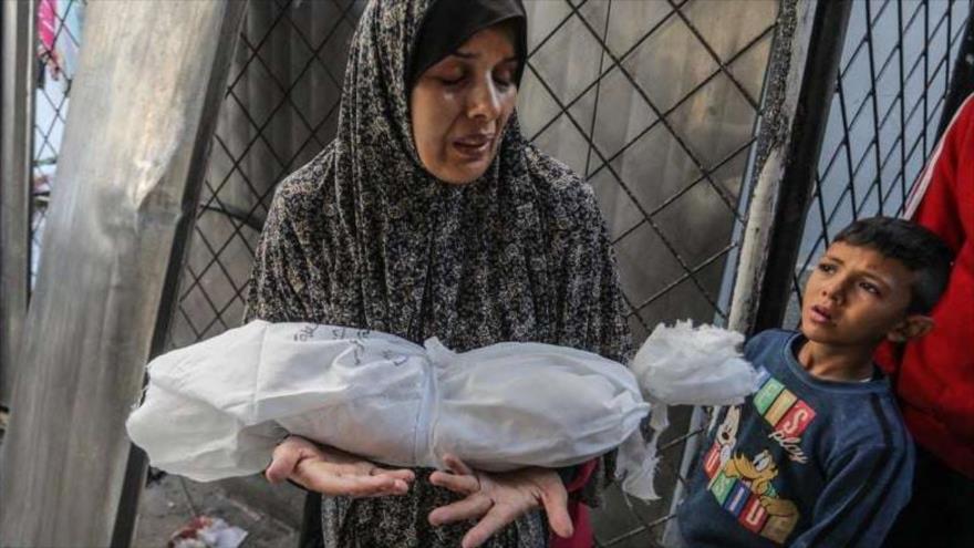 Una mujer palestina lleva envuelto el cuerpo de su bebé asesinado en un ataque israelí en Rafah, en el sur de Gaza. (Foto: DPA)