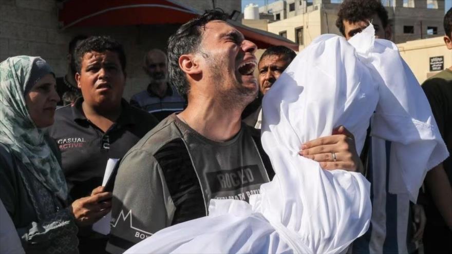 Un hombre palestino llora, cargando un cadáver. 