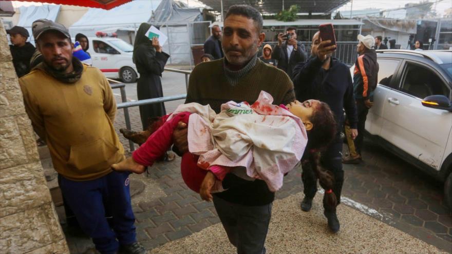 Un hombre lleva al Hospital de los Mártires de Al-Aqsa el cuerpo de una niña asesinada en un ataque israelí en Deir al-Balah, Gaza, 11 de enero de 2025.