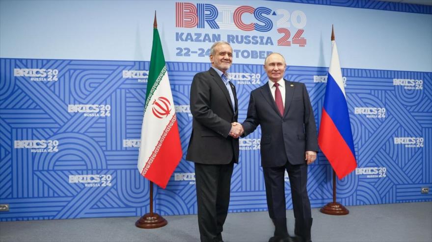 El presidente iraní, Masud Pezeshkian (izda.), y su homólogo ruso, Vladímir Putin, se estrechan la mano mientras posan para fotos en el marco de su cita al margen de la cumbre BRICS en Kazán (Rusia), 23 de octubre de 2024.