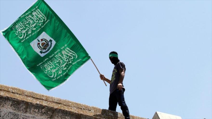 Combatiente de HAMAS sostiene una bandera del movimiento palestino en Gaza.