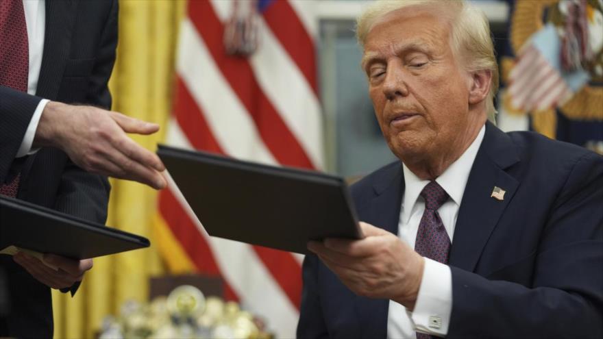 El presidente de EE.UU., Donald Trump, firma órdenes ejecutivas en el Despacho Oval, horas después de su investidura, 20 de enero de 2025.