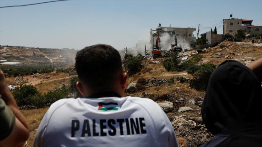 Los palestinos miran mientras los buldóceres israelíes destruyen sus viviendas en la Cisjordania ocupada.