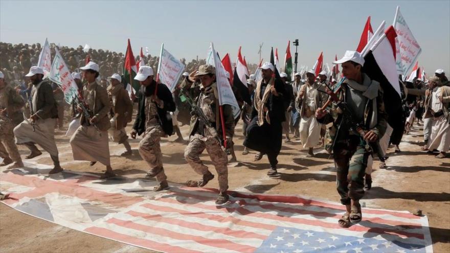 Combatientes del movimiento popular yemení Ansarolá pisotean una bandera de EE.UU. y del Reino Unido durante un desfile militar.