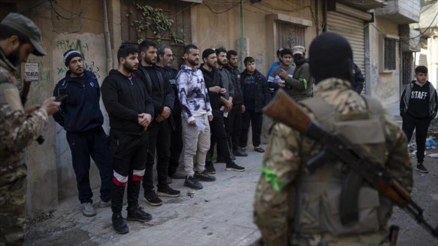 Hombres armados revisan identificaciones de la gente durante una operación en una zona residencial de Homs, Siria, 2 de enero de 2025. (Foto: AP)