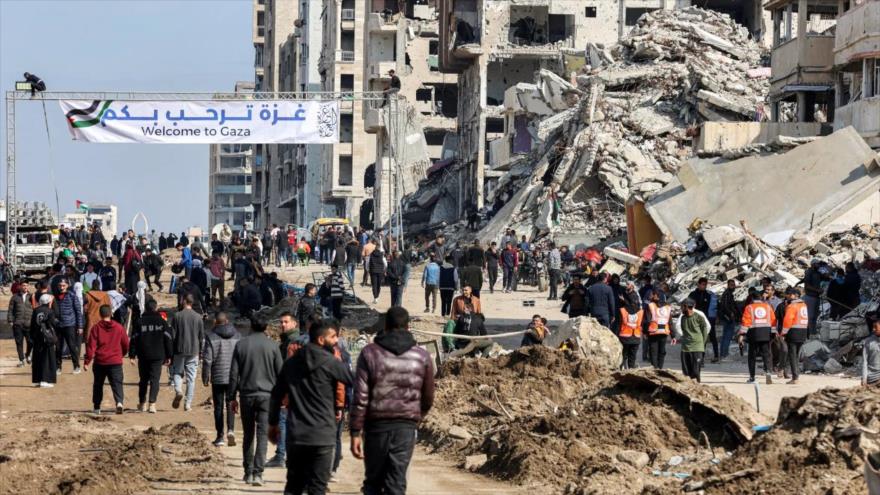 Palestinos se reúnen cerca de los escombros de un edificio derrumbado para cruzar el Corredor Netzarim, bloqueado por Israel, en el norte de la Franja de Gaza. (Foto: Getty Images)
