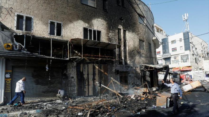 Palestinos caminan entre escombros y un edificio dañado en medio de una operación militar israelí en Yenin, en Cisjordania ocupada. (Foto: REUTERS)