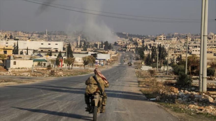 El humo se eleva mientras un insurgente del grupo del Hayat Tahrir al-Sham (HTS), conduce una motocicleta, Al-Rashideen, Alepo, Siria, 29 de noviembre de 2024. (Foto: Reuters)