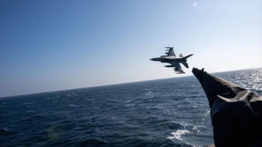 Un avión F-16 Fighting Falcon vuela junto al destructor de misiles guiados clase Arleigh Burke USS Mason (DDG 87) en el mar Rojo, 28 de diciembre de 2023.