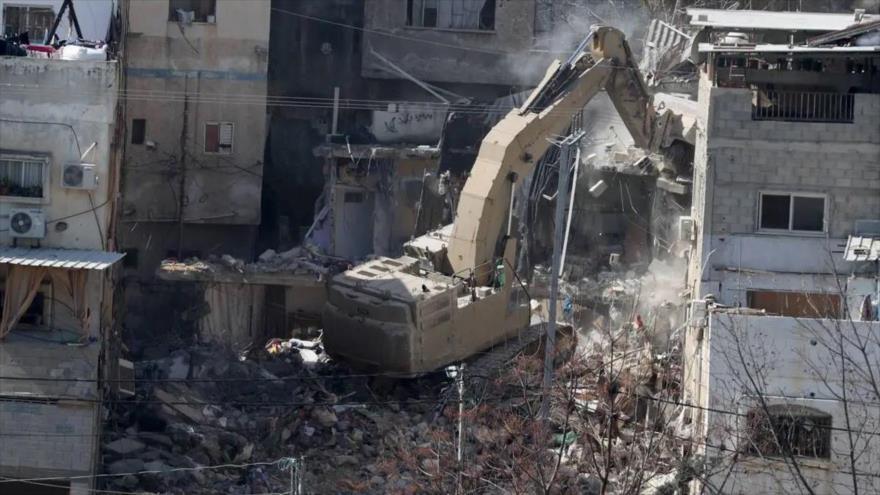 Una excavadora del ejército israelí derriba un edificio residencial en el campamento de refugiados palestinos de Tulkarem durante una operación militar israelí en curso en la Cisjordania ocupada, 18 de febrero de 2025. (Foto: Anadolu)