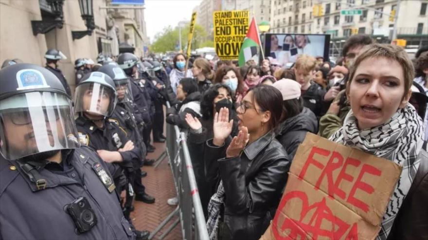 Policías estadounidenses hacen guardia mientras los manifestantes corean eslóganes en el exterior del campus de la Universidad de Columbia, 18 de abril de 2024, Nueva York.