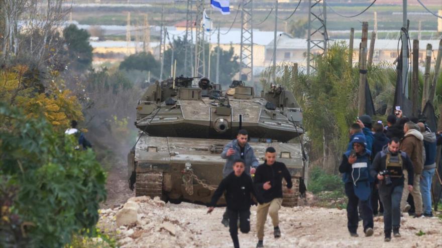 Niños y periodistas palestinos se dispersan cuando los tanques israelíes ingresan al campamento de refugiados palestinos de Yenín, Cisjordania, 23 de febrero de 2025. (Foto: AFP)