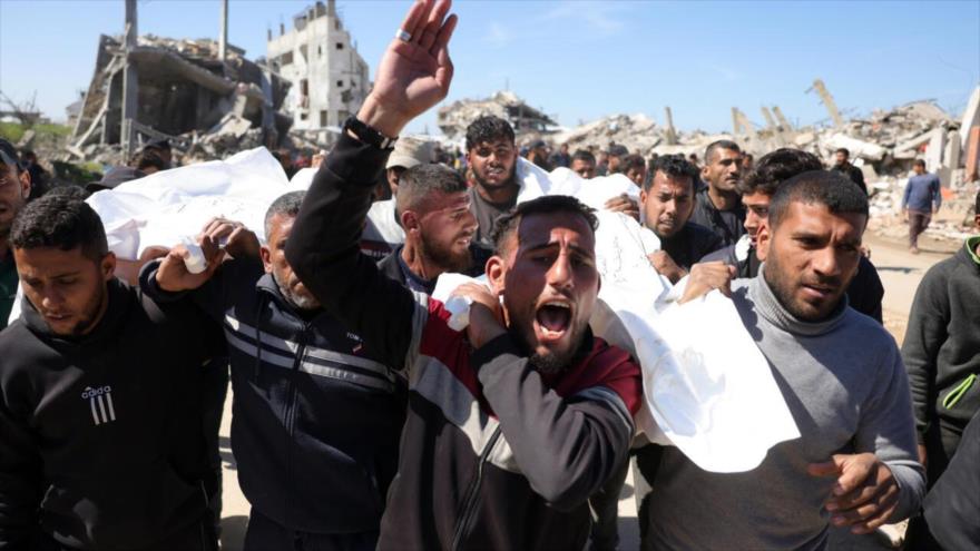 Palestinos llevan los cadáveres de dos personas asesinadas por disparos israelíes en el norte de la Franja de Gaza, 2 de marzo de 2024. (Foto: AFP)