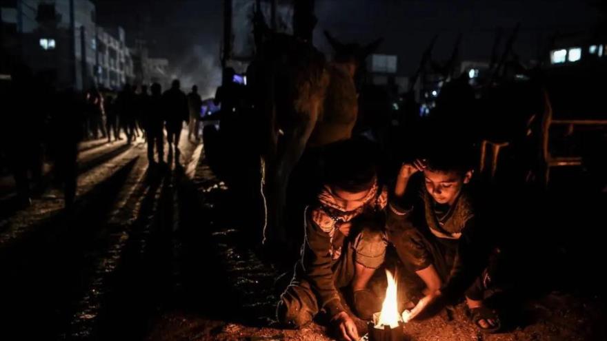 Niños palestinos encienden fuego por la noche en Jan Yunis, Gaza. (Foto: Anadolu)