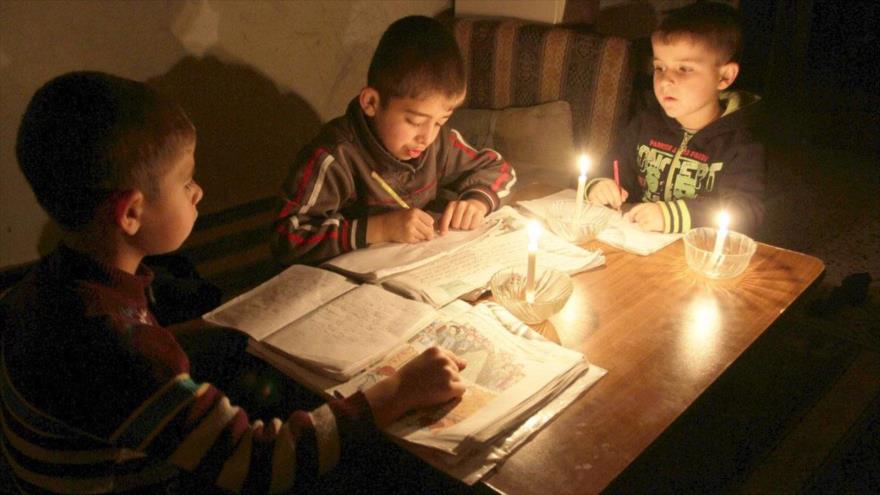 Gaza a oscuras, niños palestinos realizan sus tareas con velas ante los cortes de electricidad por Israel.