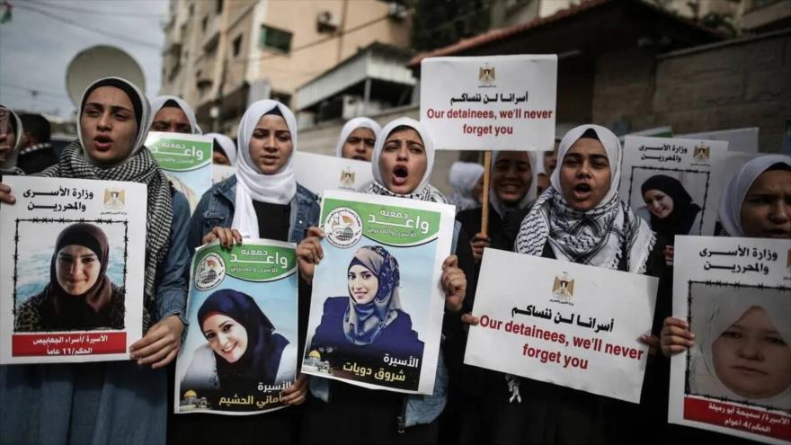 Palestinas con pancartas y fotografías de prisioneras palestinas en cárceles israelíes se manifiestan en la ciudad de Gaza, 6 de marzo de 2023.