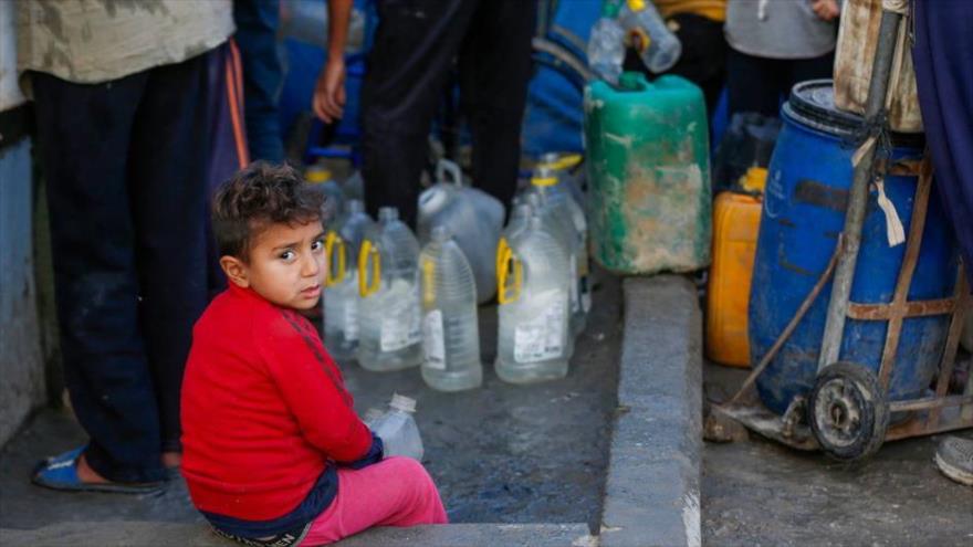 Un niño sentado junto a un punto de agua en Gaza. (foto: UNRWA)