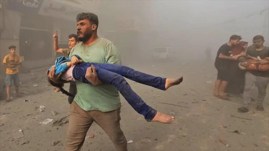 Un hombre palestino lleva a una niña herida tras un ataque aéreo israelí en el campo de refugiados de Yabalia, en el norte de Gaza. (Foto: Getty Images)