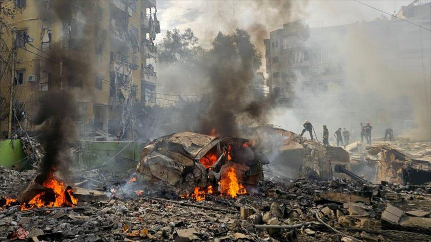 Un bombero rocía agua sobre los escombros mientras la población local se reúne en el lugar de un ataque israelí ocurrido en el sur de Beirut, capital del Líbano, en marzo de 2025. (Foto: AFP)