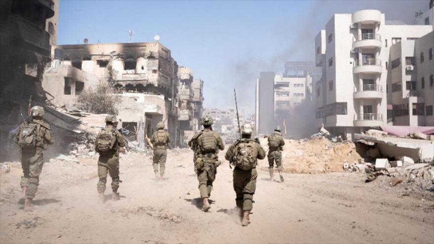 Soldados israelíes caminan entre los edificios destruidos de la asediada Franja de Gaza.