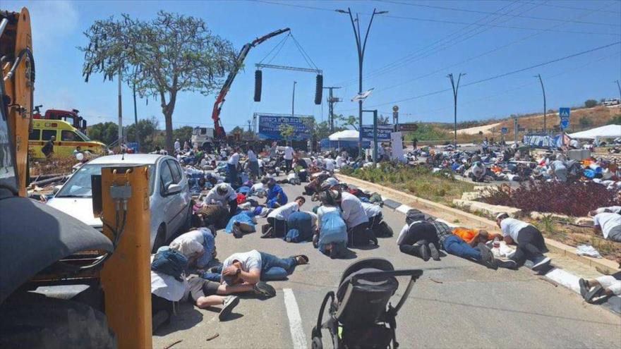 Los israelíes se resguardan al borde de una carretera tras escuchar las sirenas de alerta por un ataque con misil yemení, 13 de mayo de 2025.
