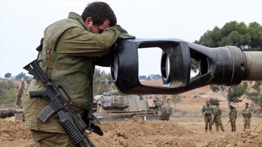 Un soldado israelí apoya su cabeza sobre el cañón de artillería de un vehículo blindado cerca de la frontera con Gaza, 9 de octubre de 2023. (Foto: AFP)