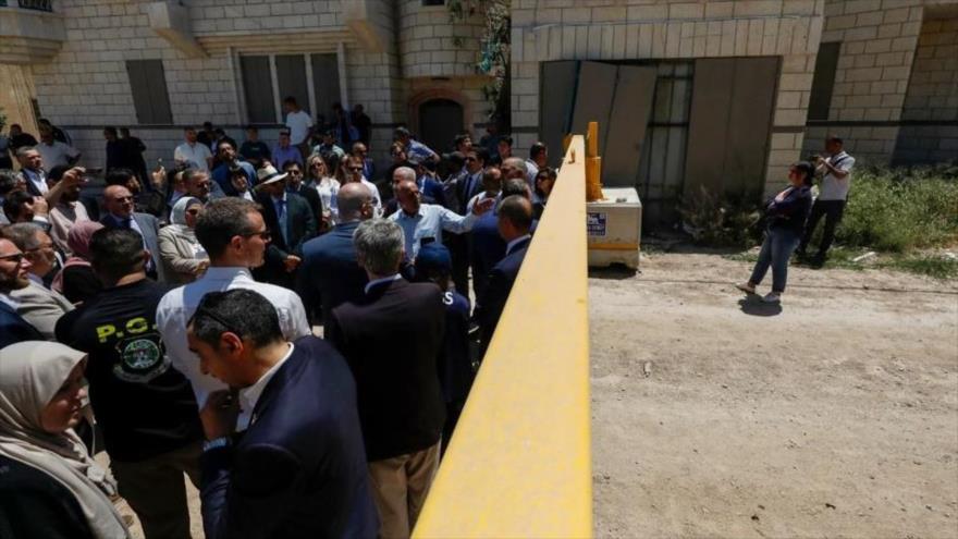 Diplomáticos extranjeros se encuentran detrás de una puerta en la entrada oriental del campamento de Yenín durante una visita oficial, 21 de mayo de 2025. (Foto: AFP)
