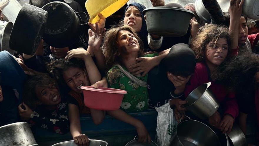 Niños palestinos se aglomeran intentando hacerse con alimentos en un centro de distribución en Gaza.