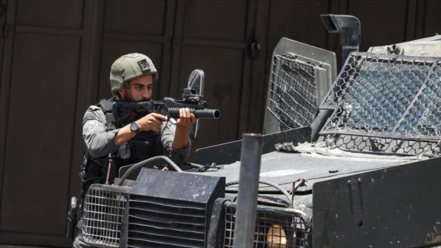 Un soldado israelí apunta con su arma hacia los palestinos en Cisjordania ocupada.