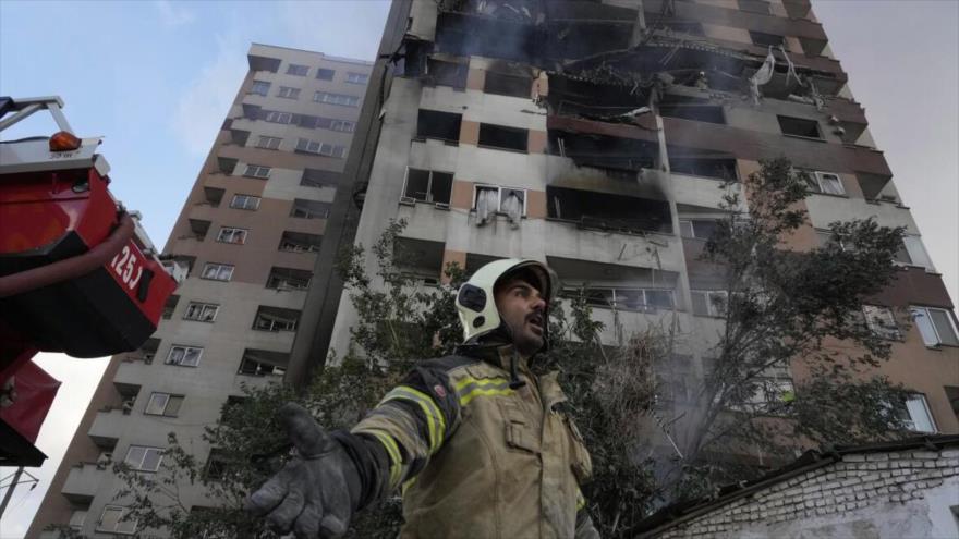 Un bombero llama a sus compañeros en el lugar de una explosión en un complejo residencial tras un ataque israelí en el norte de Teherán, 13 de junio de 2025. (Foto: AP)