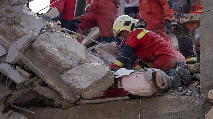 Un rescatista busca sobrevivientes entre los escombros de un edificio colapsado tras un ataque israelí en Teherán