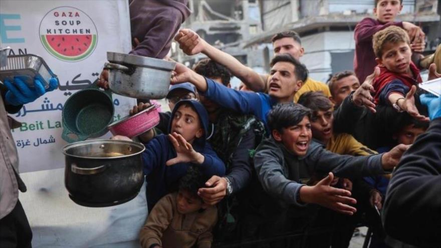 Niños palestinos desplazados hacen fila para recibir comida de un comedor social en Beit Lahia, en el norte de la Franja de Gaza, el 9 de marzo de 2025. (Foto: AFP)