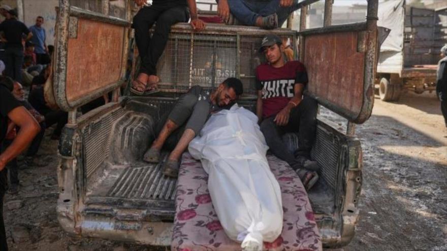 Palestinos lloran junto al cuerpo de un hombre muerto al intentar alcanzar ayuda en el cruce de Zikim, en el hospital Al-Shifa de Gaza. (Foto: AP)
