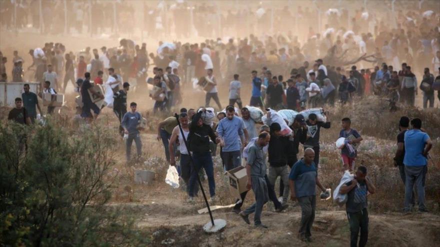 Personas transportan suministros de socorro desde un centro de distribución de ayuda en el centro de Gaza, 8 de junio de 2025. (Foto: AFP)