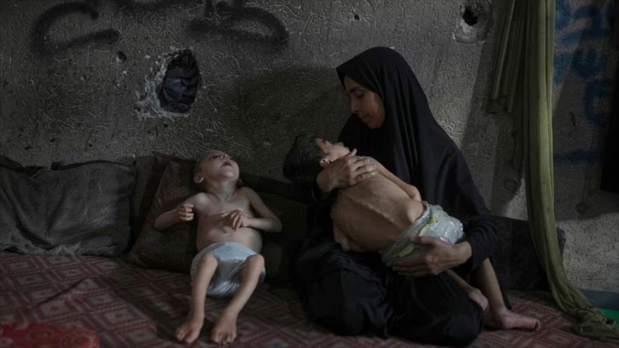 Una madre palestina, junto a sus hijos, quienes padecen desnutrición y parálisis cerebral, en una escuela en Gaza, 26 de julio de 2025. (Foto: AP)