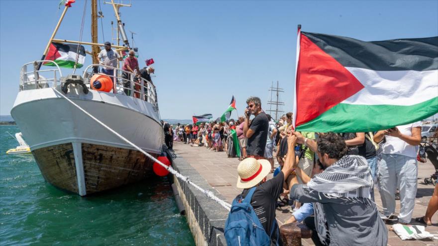 Personas con banderas palestinas se reúnen alrededor del barco ‘Handala’ de la Flotilla de la Libertad antes de su partida hacia Gaza en Sicilia, 13 de julio de 2025. (Foto: AFP)