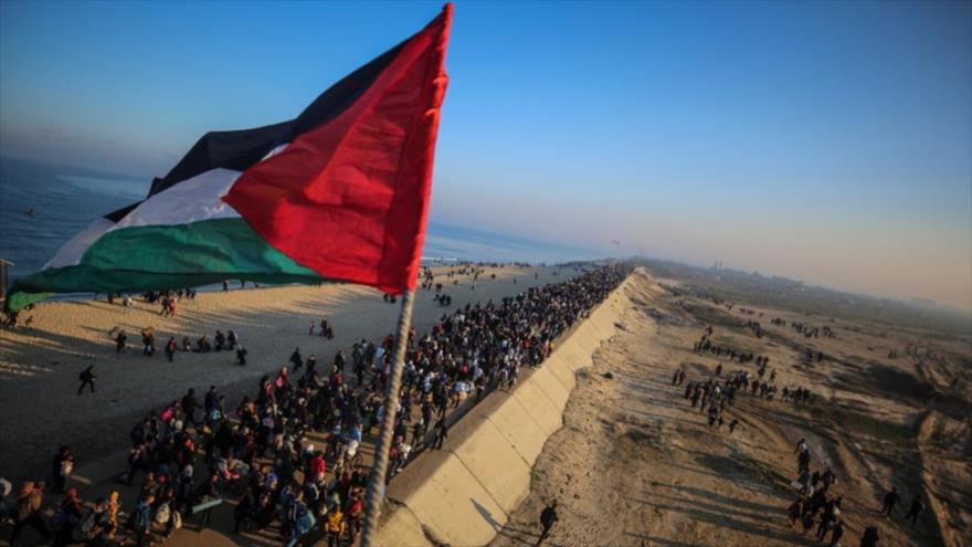 Una bandera palestina ondea mientras decenas de miles de desplazados palestinos regresan a sus casas al norte de Gaza, 27 de enero de 2025.