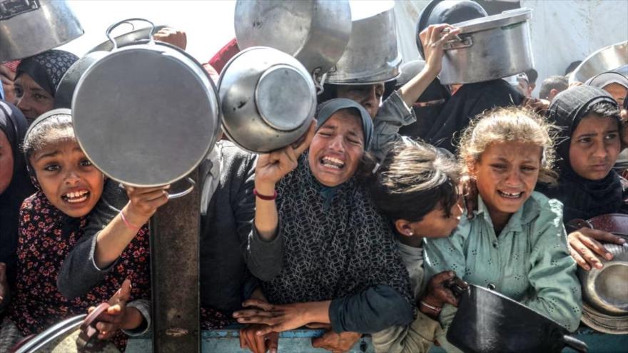 Palestinos desplazados reciben comidas distribuidas por organizaciones humanitarias en la zona de Al-Mawasi en Jan Yunis, Gaza.