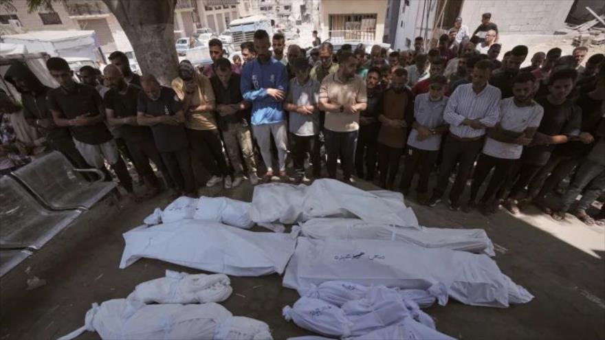 Los dolientes rezan junto a cadáveres de los palestinos muertos en un ataque israelí contra una escuela utilizada como refugio en Gaza, 3 de julio de 2025. (Foto: AP)