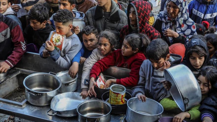 Palestinos con cuencos vacíos esperan comida en un punto de donación en Rafah. (Foto: Getty Images)
