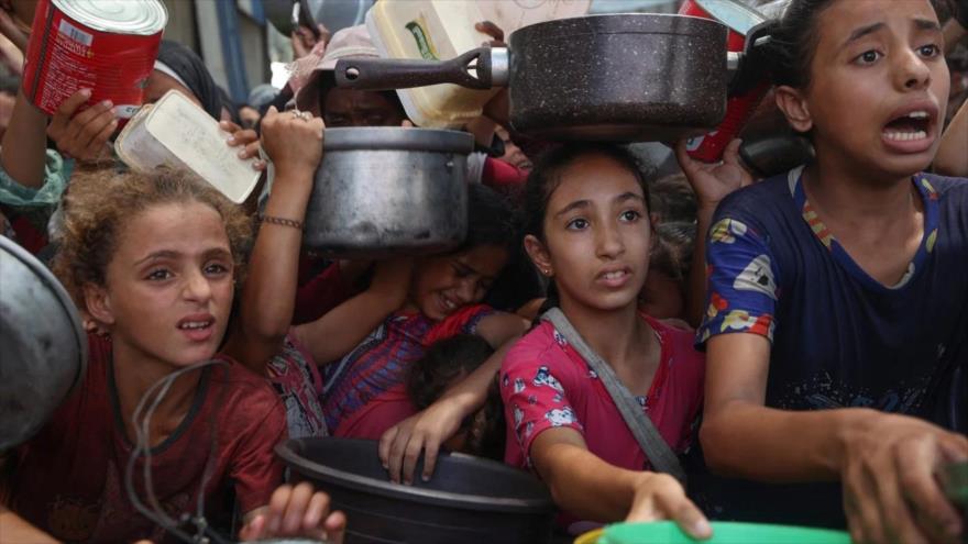 Palestinos se reúnen para recibir comidas cocinadas en un centro de distribución de alimentos en el campo de refugiados de Nuseirat en Gaza, 18 de agosto de 2025. (Foto: AFP)