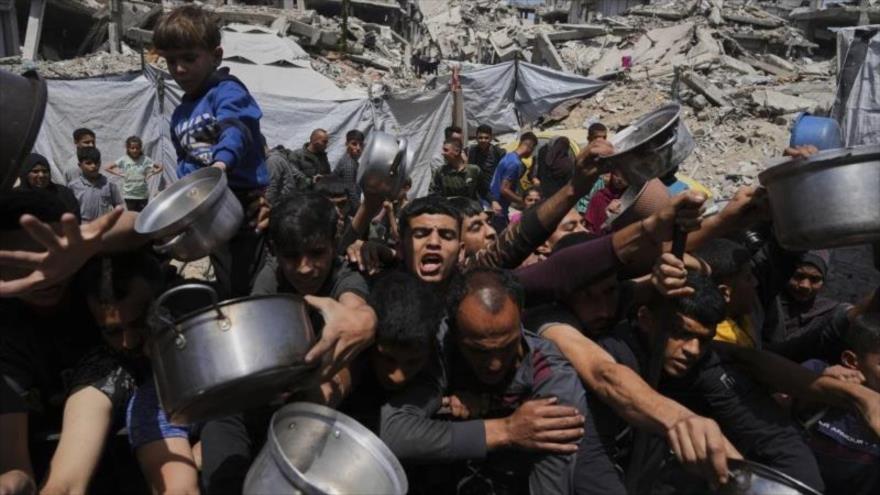 Palestinos luchan por conseguir alimentos donados en un comedor comunitario en Beit Lahia, al norte de la Franja de Gaza, 3 de mayo de 2025. (Foto: AP)
