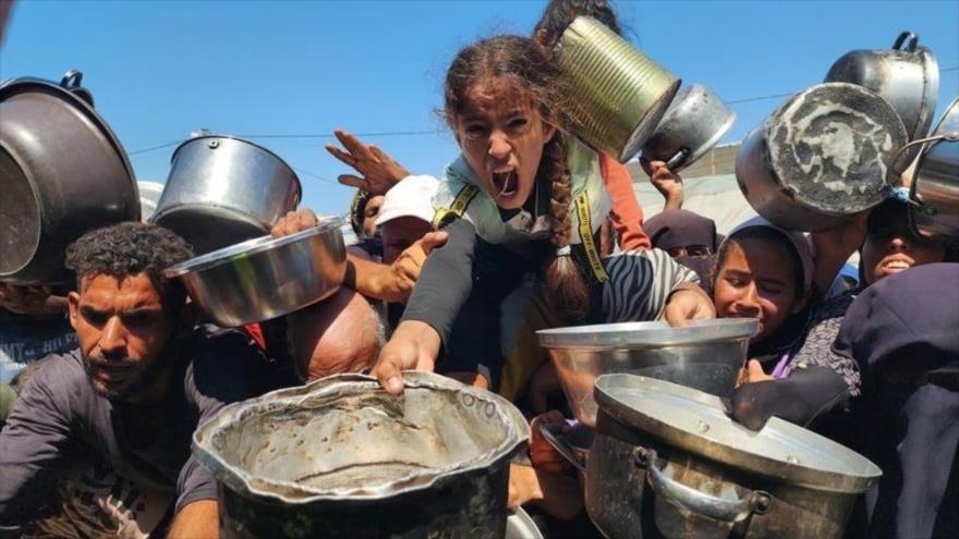 Civiles gazatíes esperan en las filas de comidas.