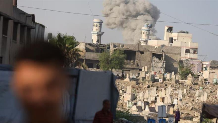 Palestinos se reúnen cerca de un cementerio mientras el humo se eleva tras una explosión durante una operación israelí, Gaza, 28 de agosto de 2025. (Foto: Reuters)