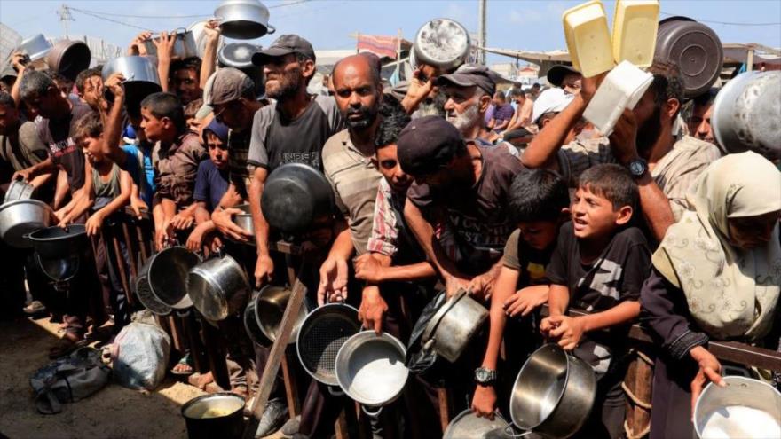 Palestinos sostienen ollas y recipientes mientras esperan recibir comida de un comedor social en Jan Yunis, al sur de Gaza, 21 de agosto de 2025. (Foto: Reuters)