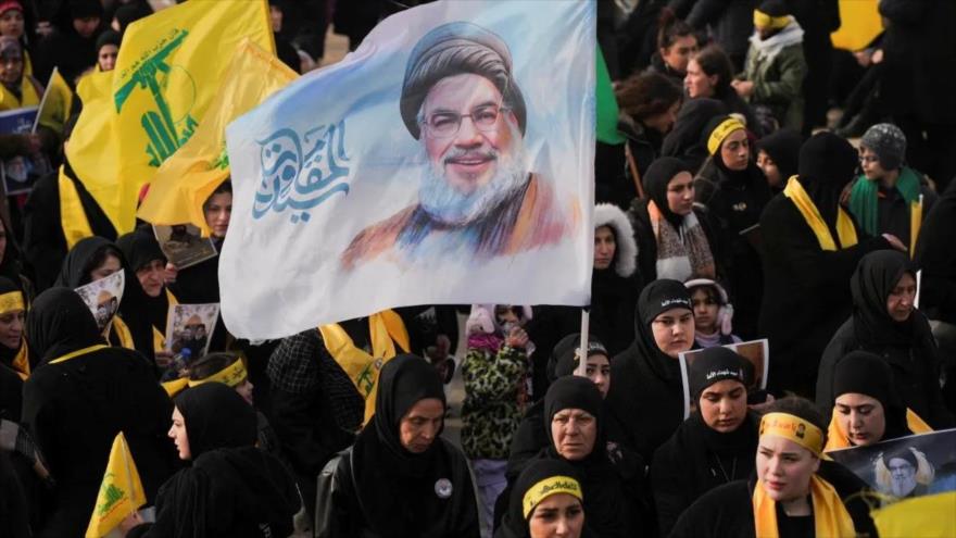 Una mujer sostiene una bandera con la imagen del líder mártir de Hezbolá, Seyed Hasan Nasralá. 