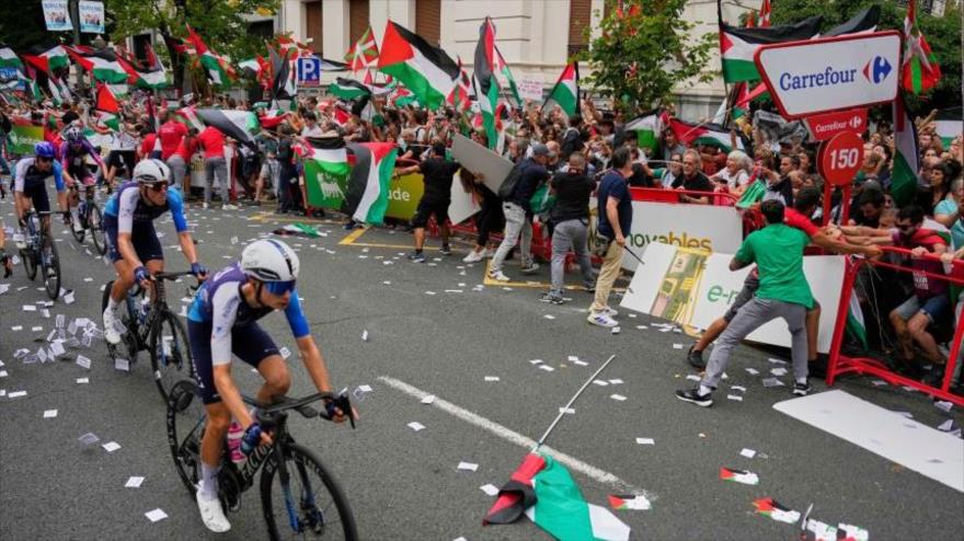Ciclistas del equipo Israel-Premier Tech compiten mientras espectadores con banderas palestinas intentan interrumpir la 11.ª etapa de la Vuelta a España, de Bilbao a Bilbao, 3 de septiembre de 2025. (Foto: AP)