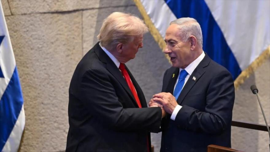 El presidente de EE.UU., Donald Trump (izda.), estrecha la mano del primer ministro israelí, Benjamín Netanyahu, en el parlamento del régimen sionista en Al-Quds, 13 de octubre de 2025. 
